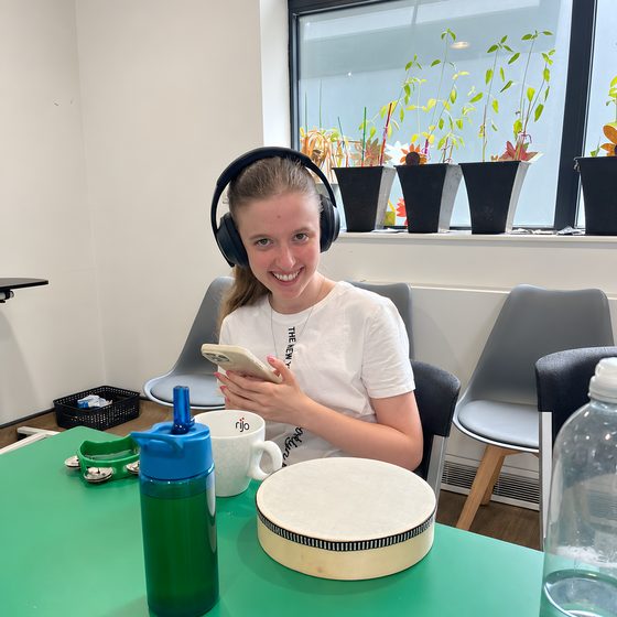 A member wearing headphones and smiling at a table set up for a music session.