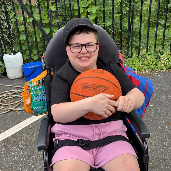 A member holding a basketball outdoors at the park.